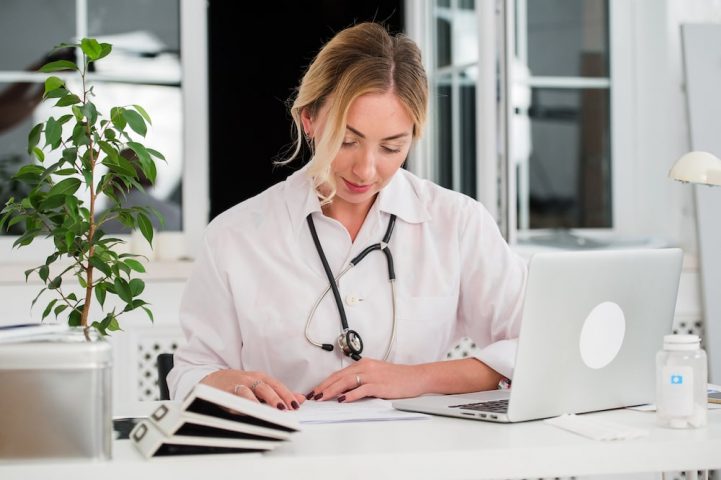 female doctor reading documents at office desk